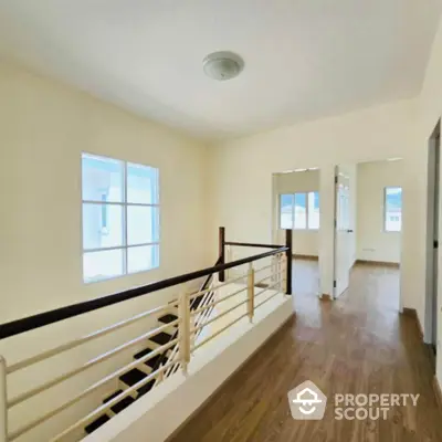 Bright hallway with wooden flooring and modern railing in a spacious home