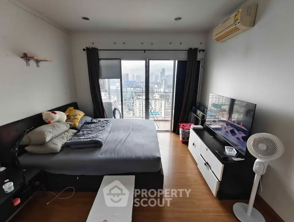 Modern bedroom with city view, featuring sleek furniture and large windows for natural light.