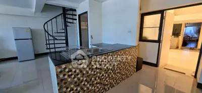 Modern kitchen with spiral staircase and stylish island in open layout apartment.