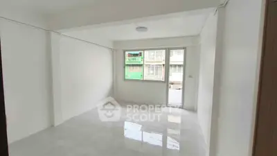 Spacious unfurnished room with large window and balcony access in modern apartment.