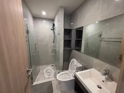 Modern bathroom with glass shower and sleek fixtures in contemporary apartment.