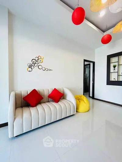 Modern living room with stylish sofa, red cushions, and unique wall decor