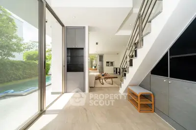 Modern open-plan living area with pool view and sleek staircase design.