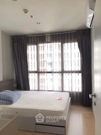 Modern bedroom with large window and stylish curtains in a contemporary apartment.