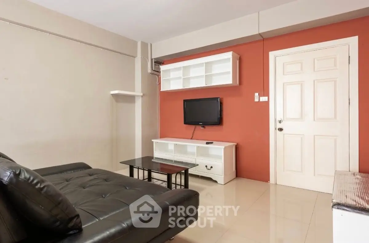 Modern living room with sleek black leather sofa and wall-mounted TV, perfect for relaxation.