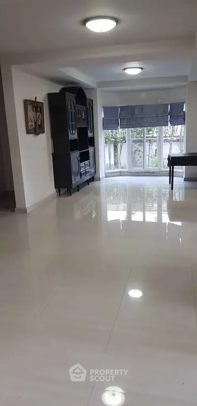 Spacious living room with glossy tiled floors and large windows.