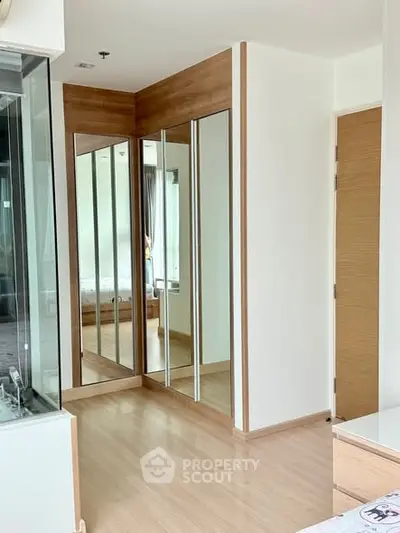 Modern bedroom with mirrored wardrobe and wooden flooring
