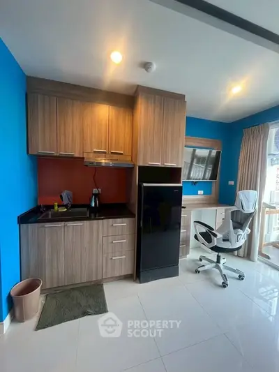 Modern kitchen with sleek cabinetry and integrated workspace in bright apartment.