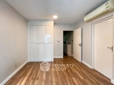 Spacious empty room with wooden flooring and built-in wardrobe