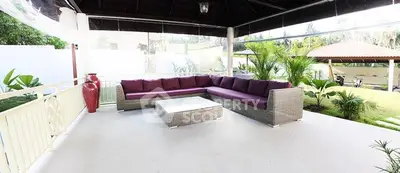 Spacious covered patio with modern outdoor seating and lush garden view.
