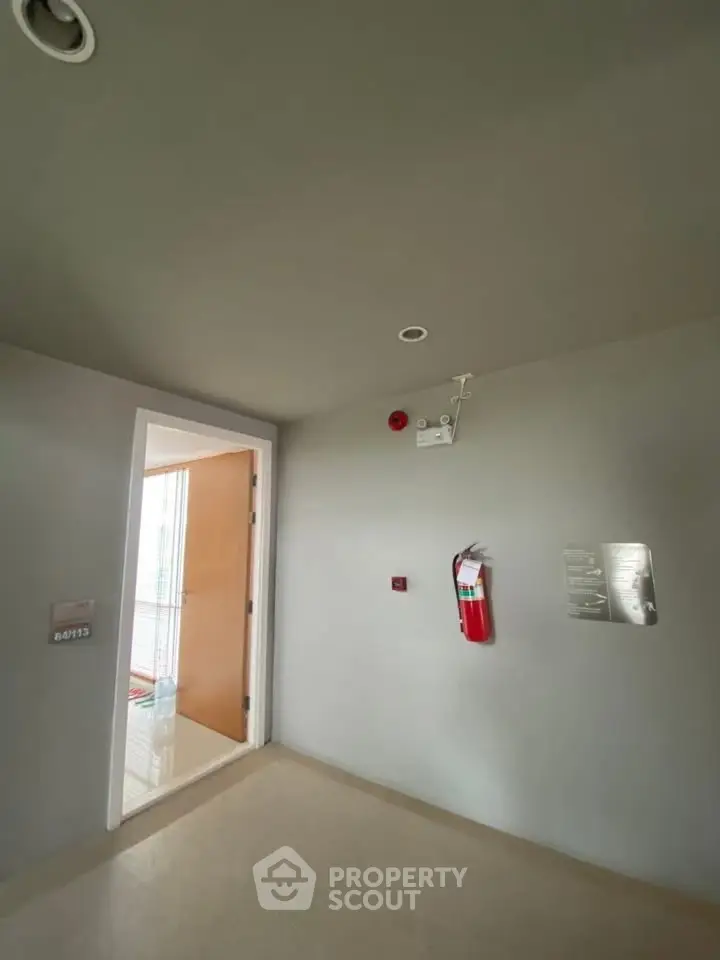 Modern building hallway with fire safety equipment and open door.