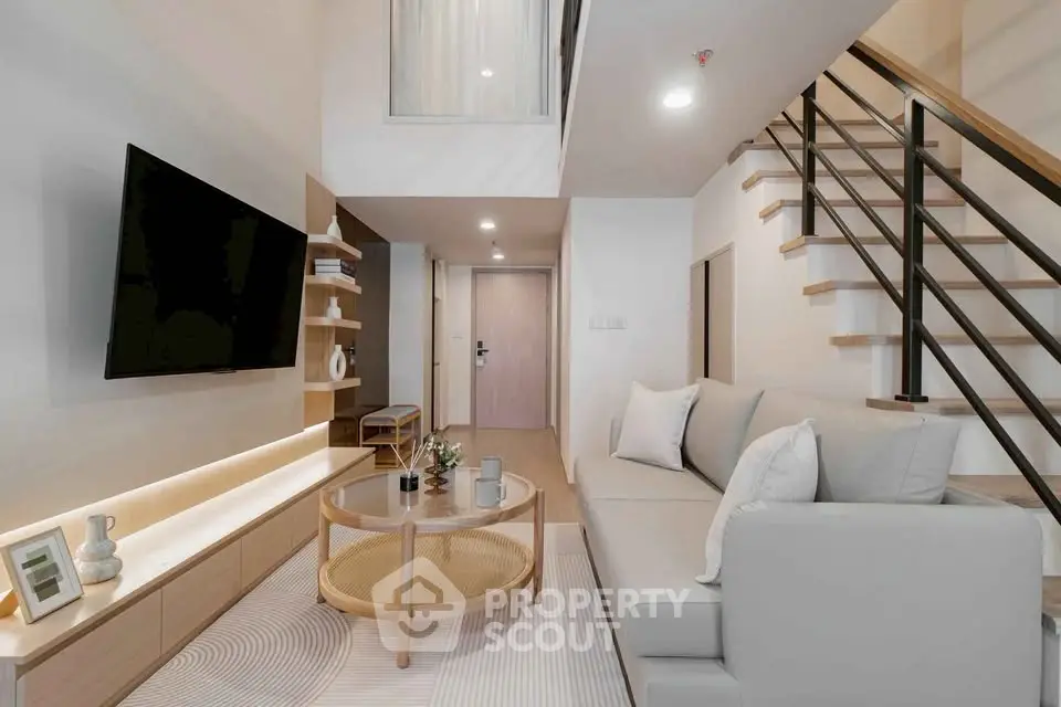 Modern living room with stylish furniture and open staircase in a contemporary apartment.