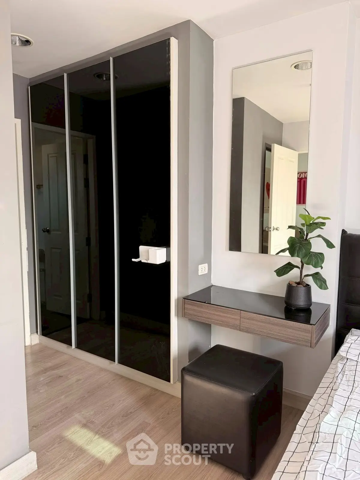 Modern bedroom with sleek mirrored wardrobe and stylish vanity area.