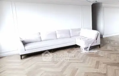 Spacious living room with elegant herringbone flooring and modern white sofa.