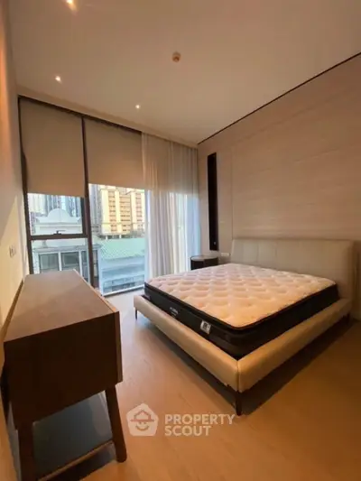 Modern bedroom with city view, featuring a stylish bed and wooden furniture.