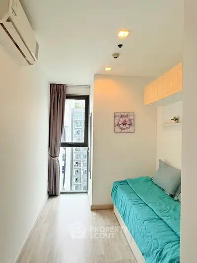 Modern bedroom with large window and stylish decor in urban apartment.