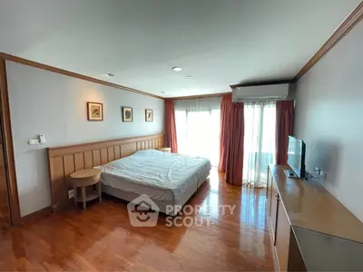 Spacious bedroom with wooden flooring and large windows for natural light.