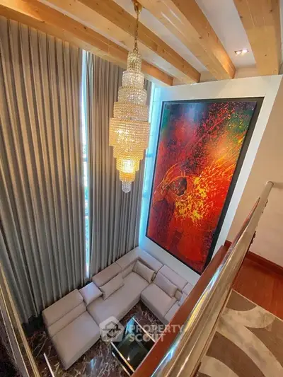 Luxurious living room with high ceilings, elegant chandelier, and modern art piece.