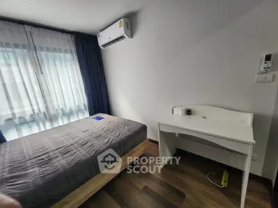 Modern bedroom with air conditioning and study desk, featuring a cozy bed and wooden flooring.