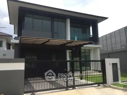 Modern two-story house with sleek design and gated entrance in a suburban neighborhood.