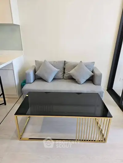 Modern living room with stylish gray sofa and sleek glass coffee table in a cozy apartment.
