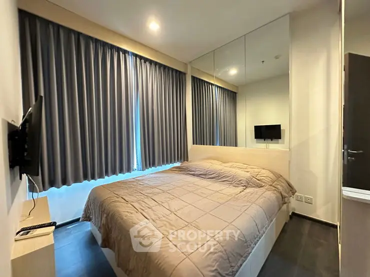 Cozy bedroom with modern decor and wall-mounted TV, featuring large windows and elegant curtains.