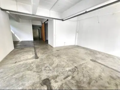Spacious industrial-style room with concrete flooring and white walls, ideal for creative workspace.