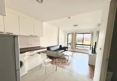 Modern open-plan living room with kitchen, featuring sleek furniture and large windows.