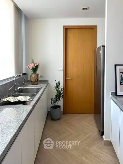 Modern kitchen with sleek countertops and stainless steel fridge in a bright, minimalist design.