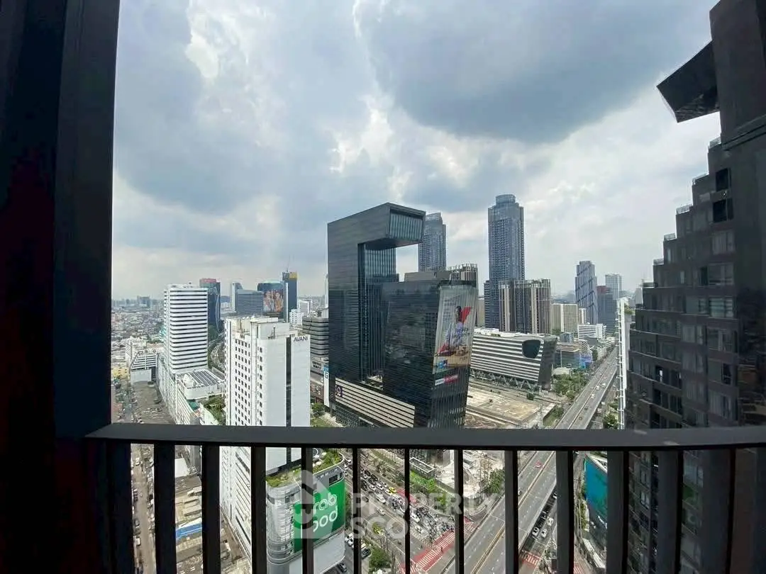 Stunning cityscape view from a high-rise balcony with modern skyscrapers and cloudy sky.