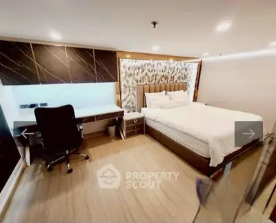 Luxurious bedroom with modern decor and spacious layout, featuring a stylish desk and comfortable chair.