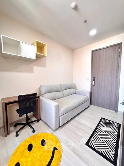 Modern living room with stylish sofa and workspace, featuring a cheerful smiley rug.