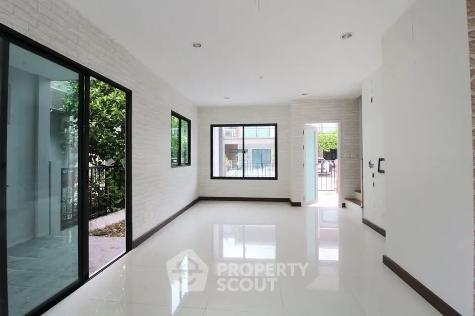 Spacious modern living room with large windows and glossy white tiles