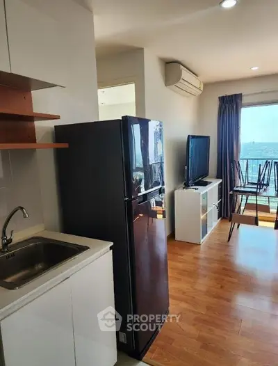 Modern apartment interior with kitchen and living room, featuring wooden floors and a scenic balcony view.