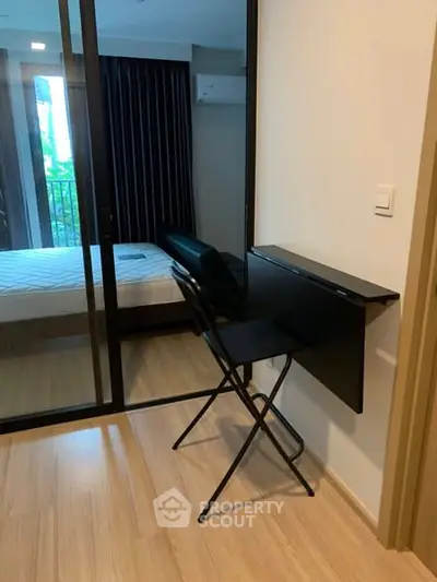 Compact bedroom with foldable desk and chair, modern design, and large window view.