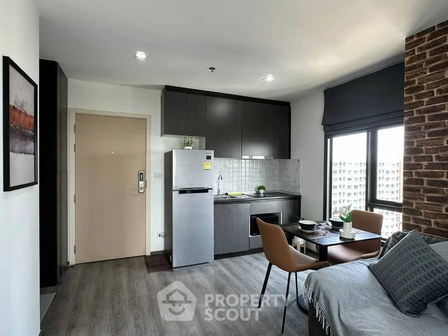 Modern studio apartment with sleek kitchen and cozy living area, featuring large window for natural light.