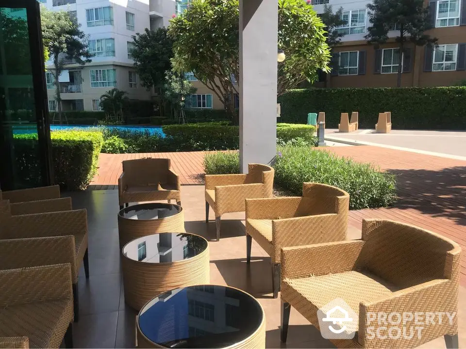 Modern outdoor seating area with wicker chairs near pool in residential complex