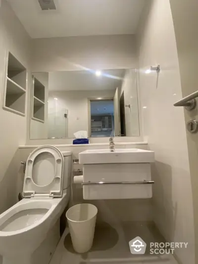 Modern bathroom with sleek fixtures and large mirror in contemporary apartment.