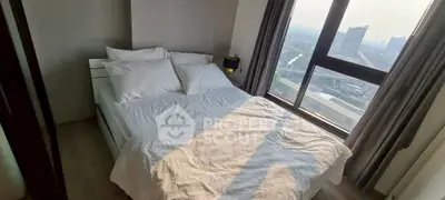 Cozy bedroom with large window offering stunning city view, perfect for relaxation and comfort.