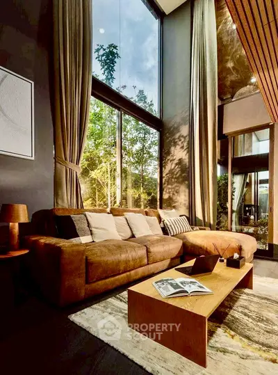 Luxurious living room with high ceilings and large windows offering a stunning garden view.