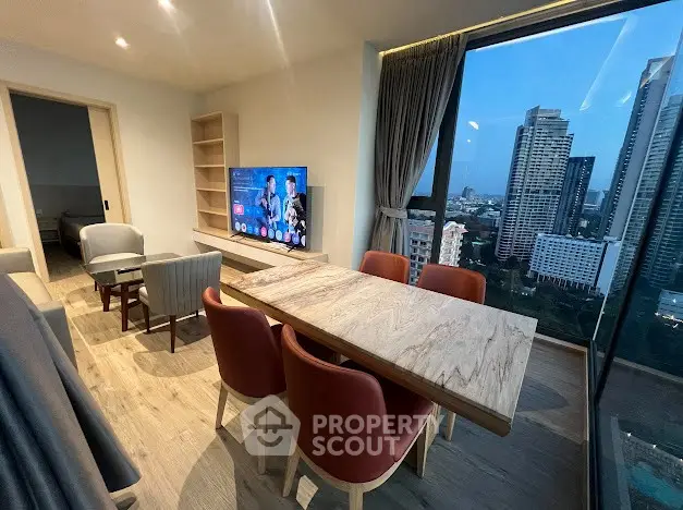 Modern living room with city view, stylish furniture, and large windows in a high-rise apartment.