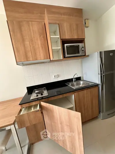 Modern compact kitchen with wooden cabinets and stainless steel appliances