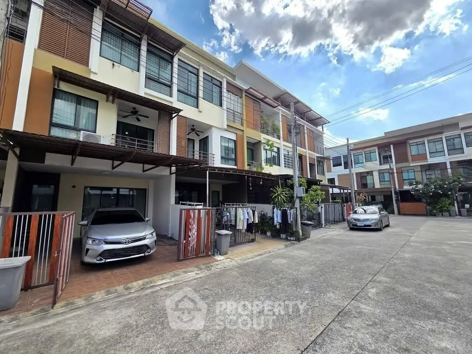 Modern townhouse exterior with carport and driveway in a sunny neighborhood.