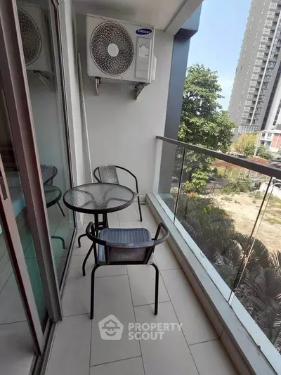 Charming balcony with glass railing and outdoor seating, perfect for relaxation with a view of the cityscape.
