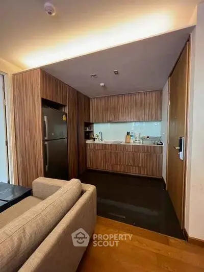 Modern kitchen with wooden cabinetry and sleek appliances in a cozy apartment setting.