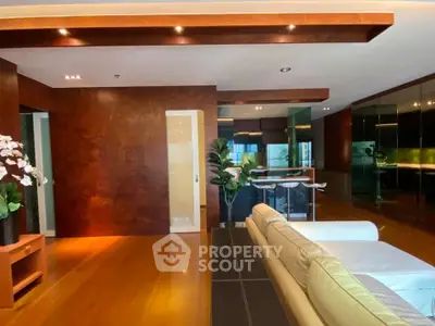 Luxurious modern living room with elegant wooden accents and open kitchen layout.