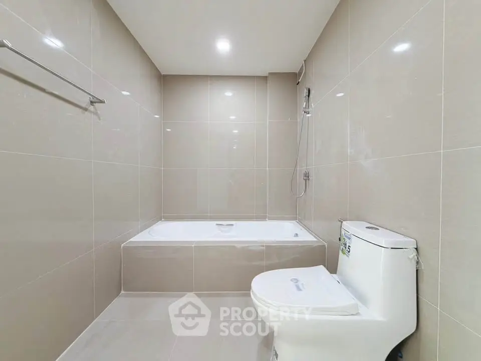 Modern bathroom with sleek tiles and a built-in bathtub, perfect for relaxation.