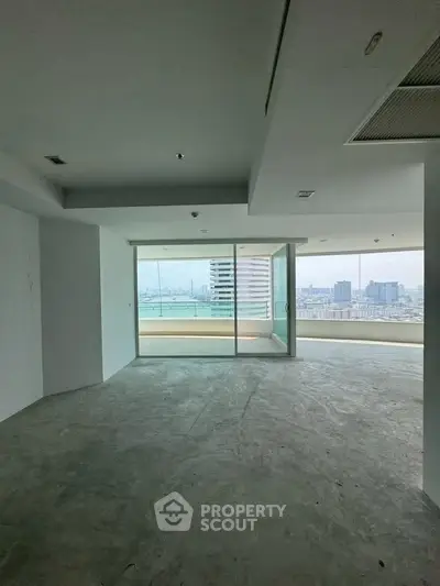 Spacious unfurnished living room with large windows offering panoramic city views.