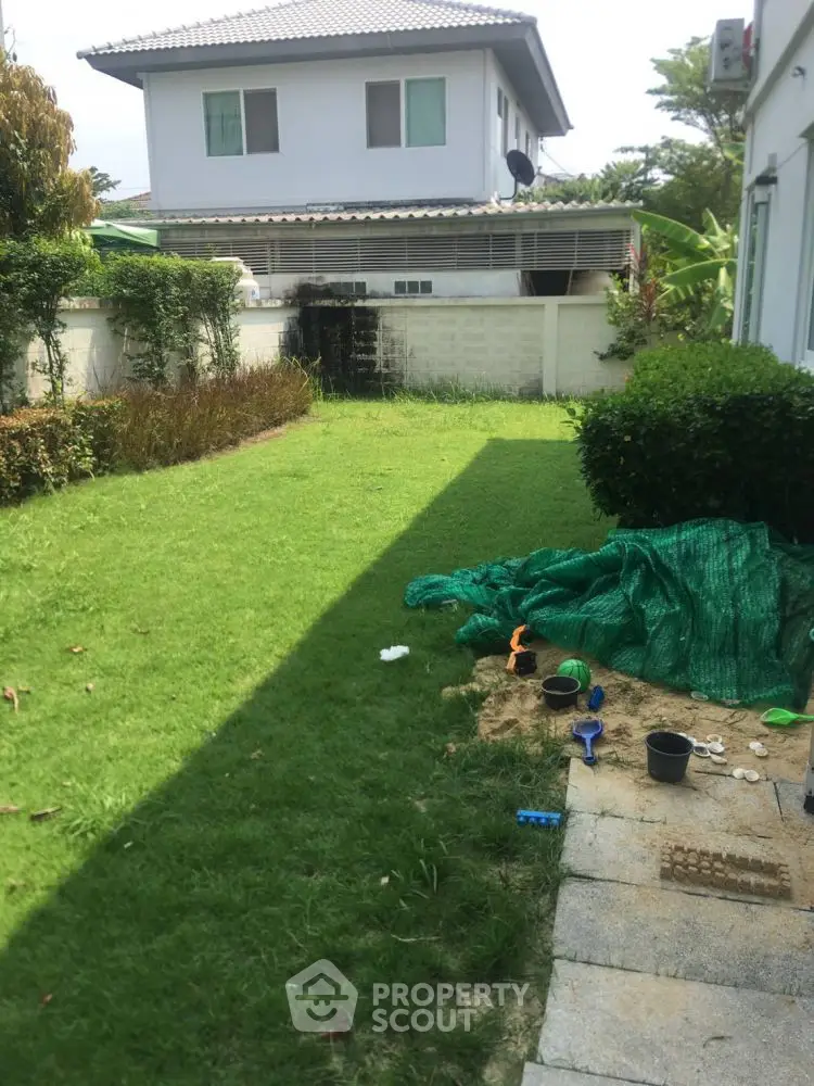 Charming backyard garden with lush green lawn and cozy play area, perfect for family relaxation and outdoor activities.