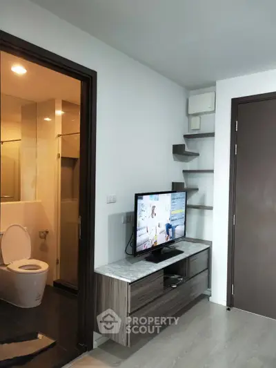 Modern apartment interior with sleek TV unit and bathroom view, showcasing contemporary living space.